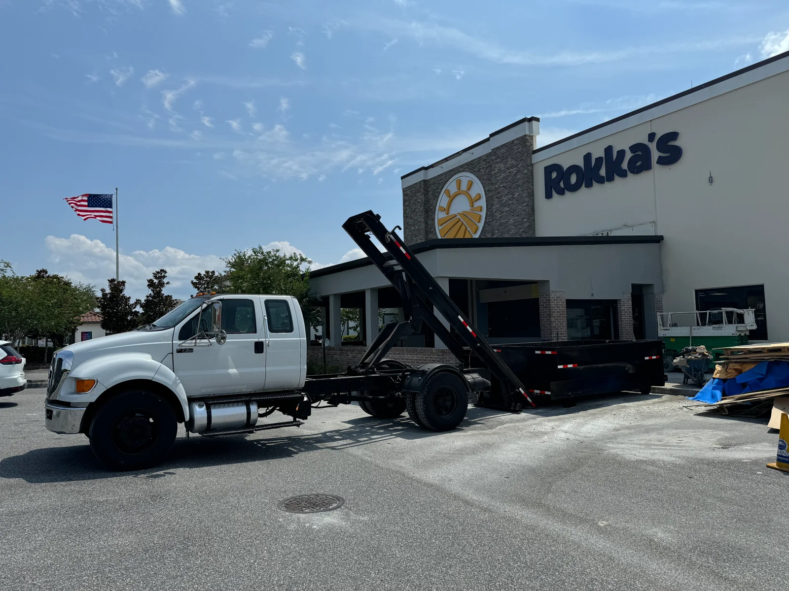 GM truck and roll-off dumpster at a commercial delivery